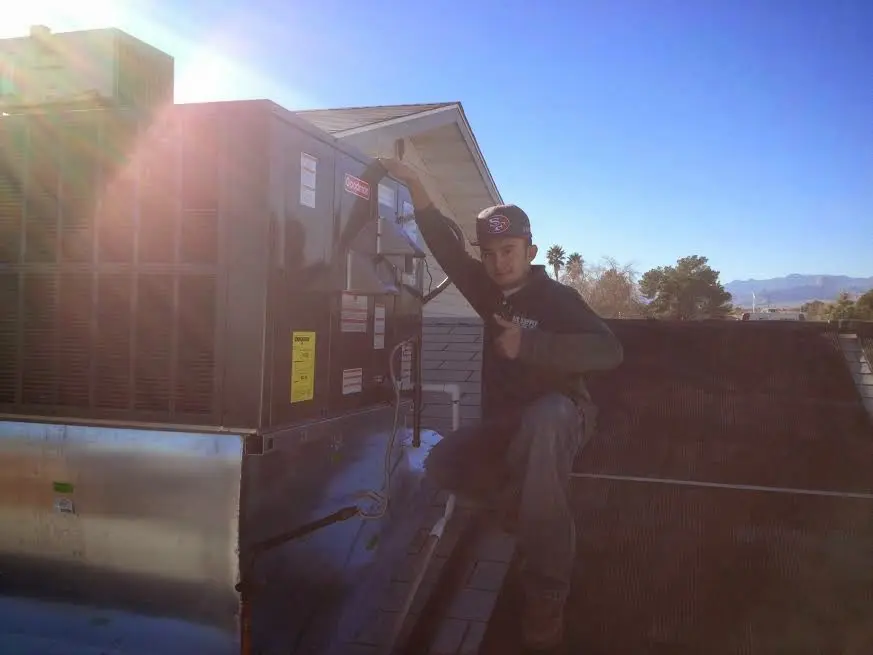 HVAC technician performing AC Tune-Up on a rooftop unit in Pelham